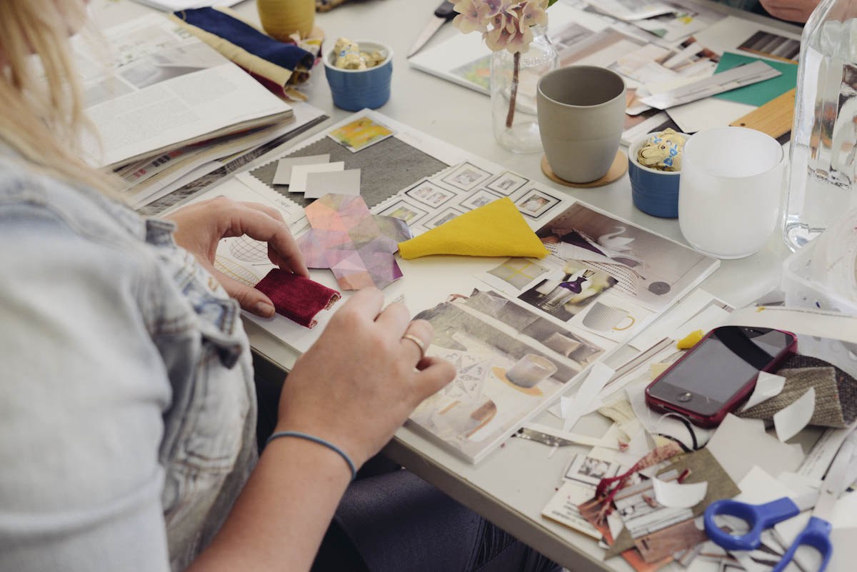 a woman works at a desk surrounded by craft materials